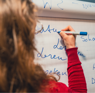 Een vrouw die wat op een whiteboard schrijft.
