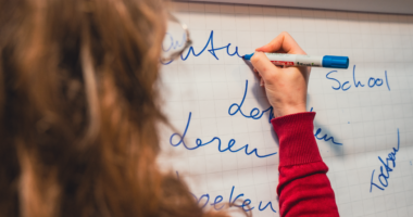 Een vrouw die wat op een whiteboard schrijft.